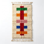 Colorful Moroccan runner rug — cream wool with red spine and green, orange, pink and blue crossbars, flat lay