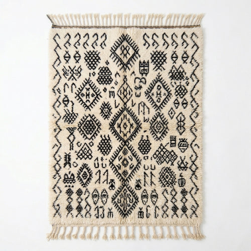 Berber script Azilal rug — ivory wool with dense black tribal symbols, flat lay