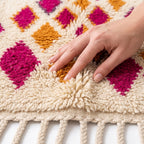 Coral Bloom Azilal rug — hand resting on the soft wool pile