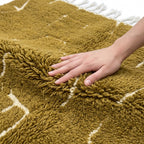 Golden Ochre Mrirt rug — hand resting on the soft wool pile