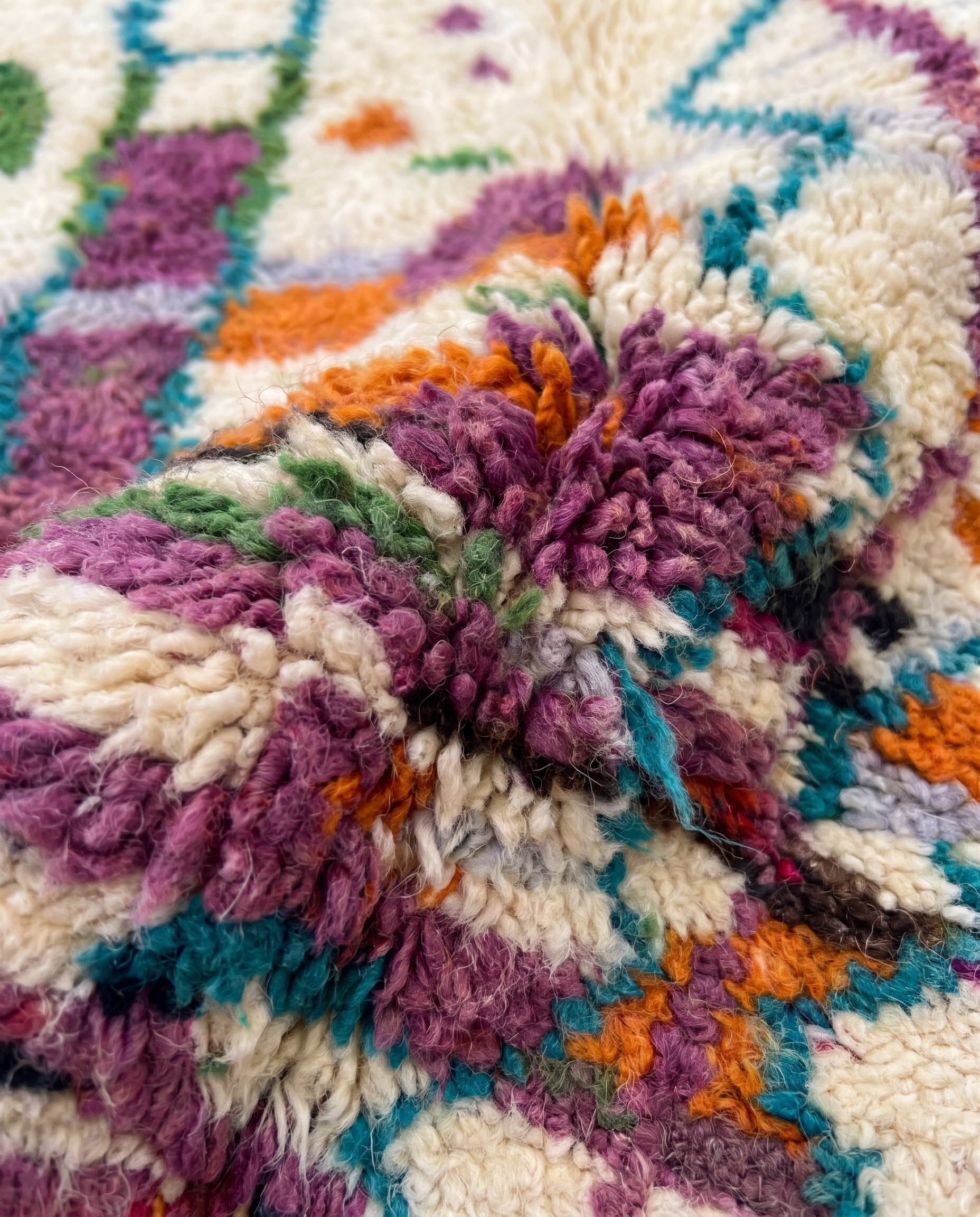 Close-up of hand-knotted wool pile with violet, orange and teal Berber motifs — Boujaad rug texture
