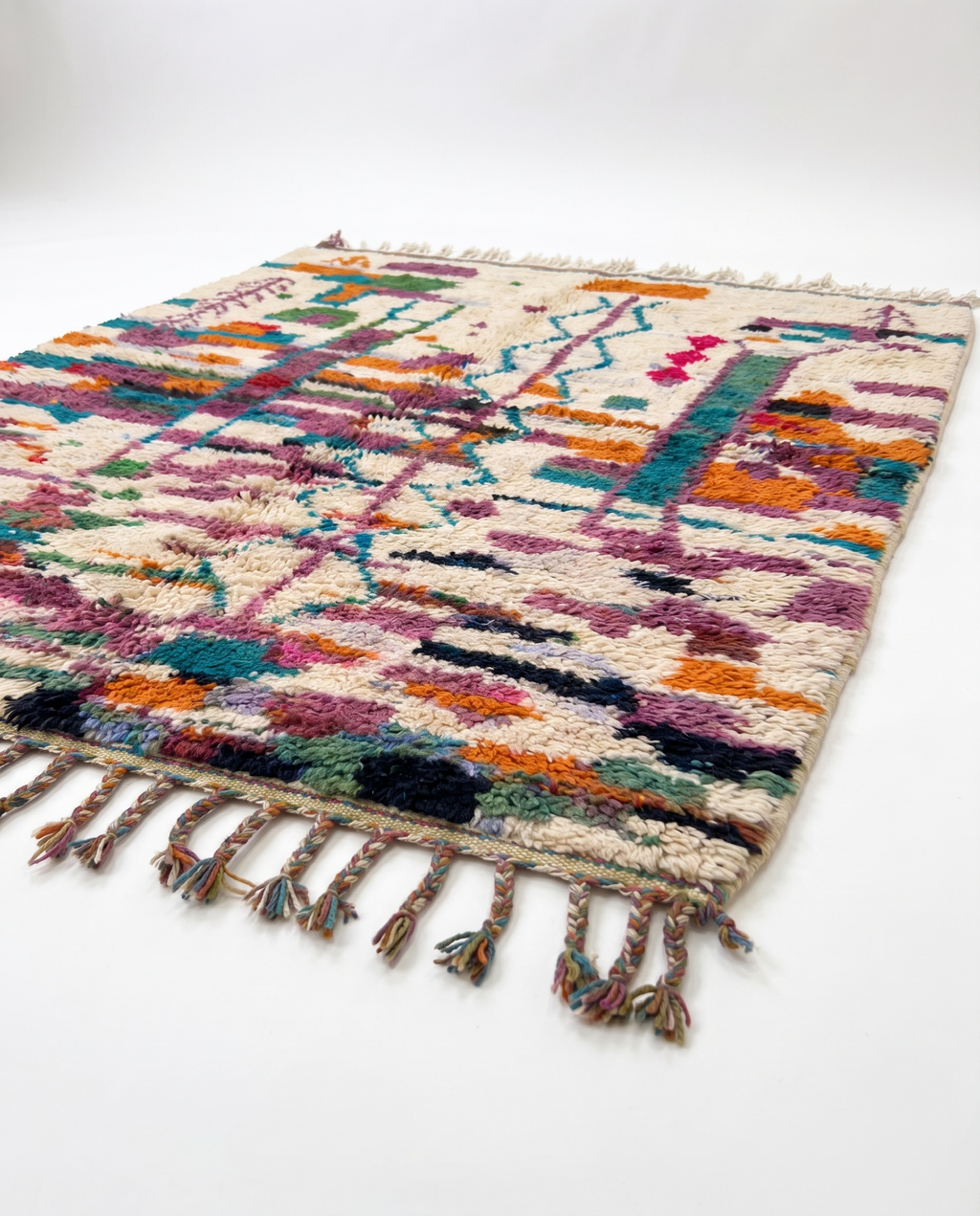 Side view of Boujaad rug showing wool pile height and fringe on white studio background