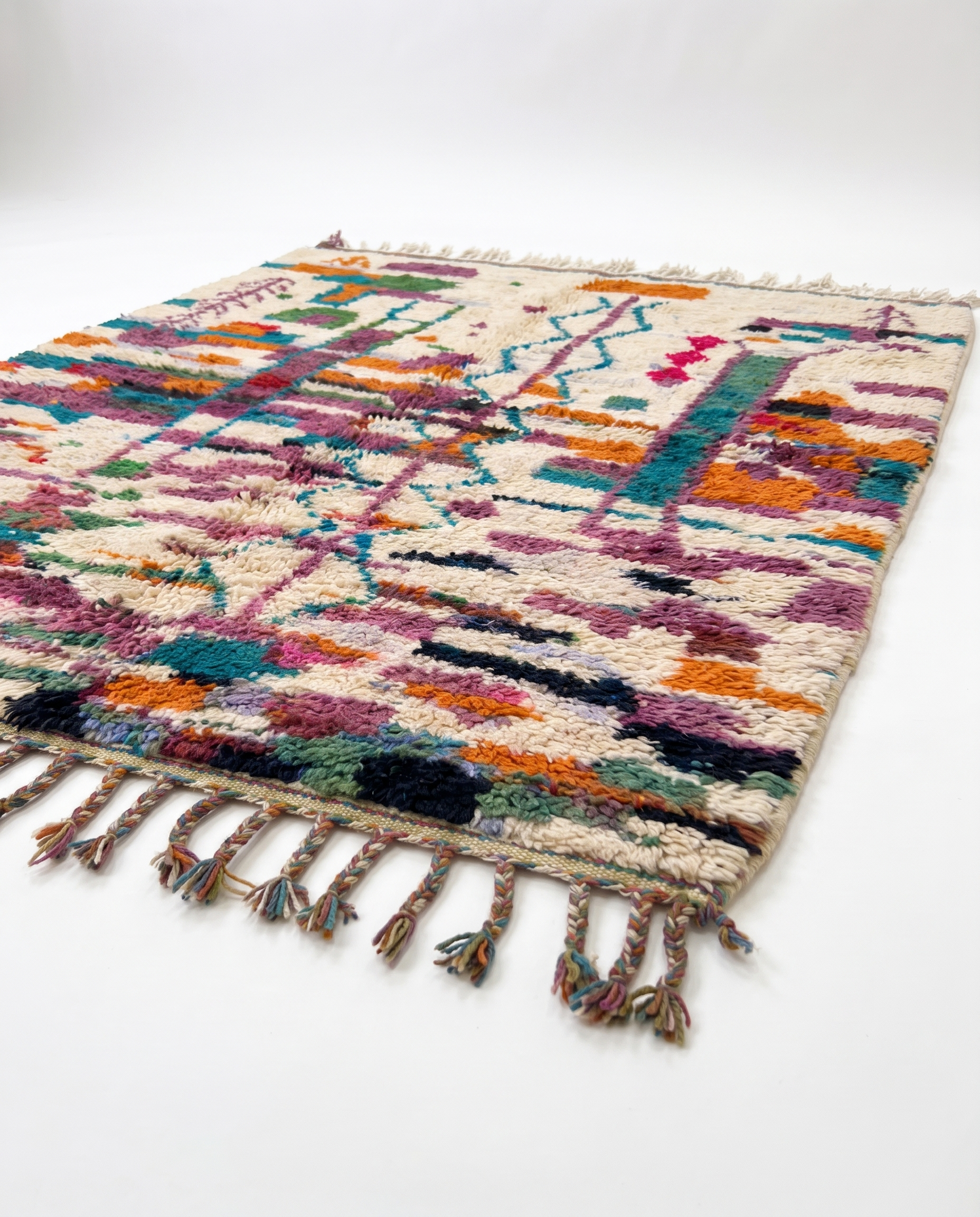 Side view of Boujaad rug showing wool pile height and fringe on white studio background