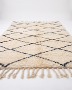 Side view of Beni Ourain rug showing wool pile height and braided fringe on white studio background