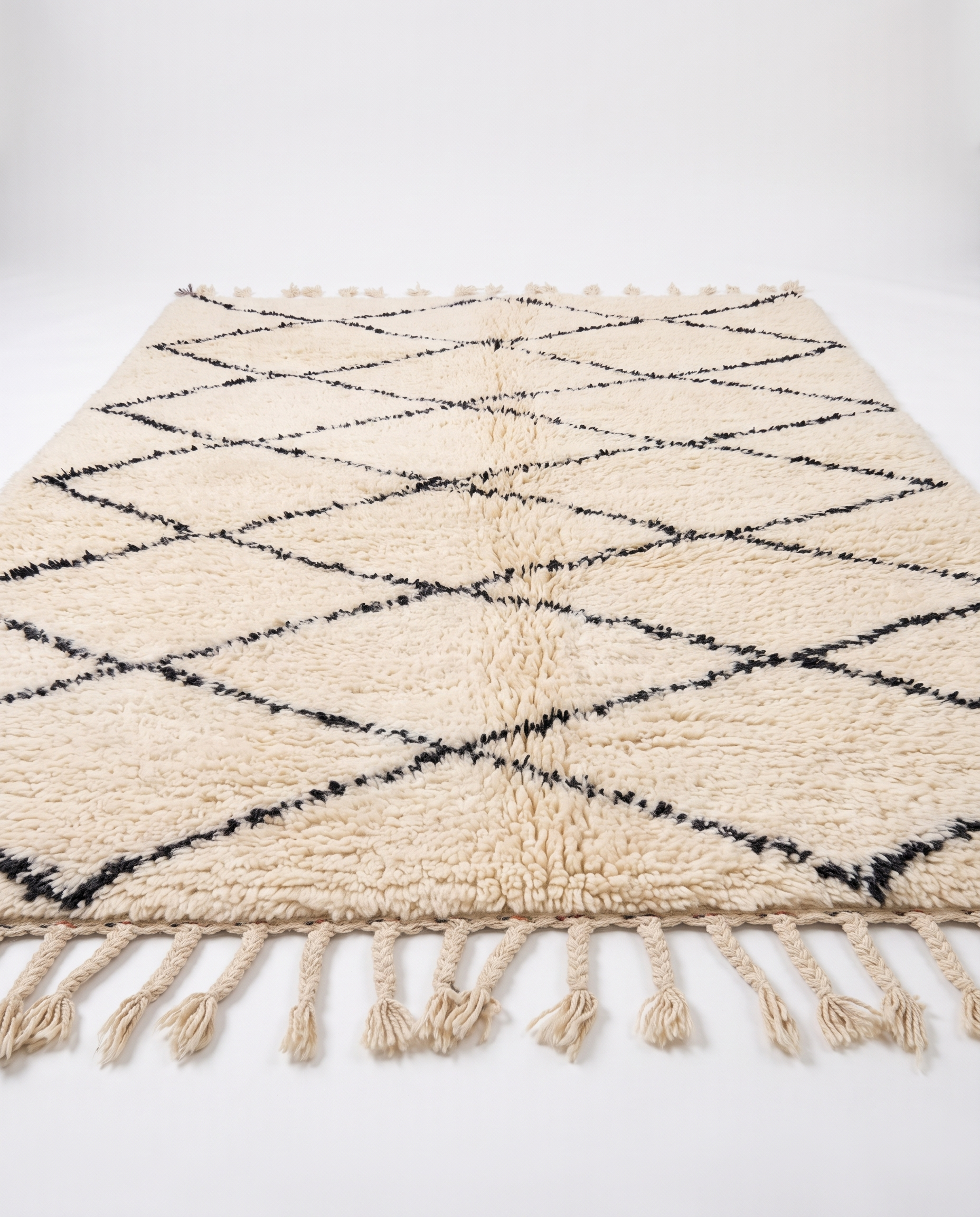 Side view of Beni Ourain rug showing wool pile height and braided fringe on white studio background