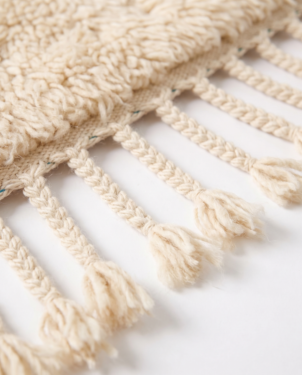 Hand-braided wool fringe tassels of premium Mrirt rug — detail on white studio background