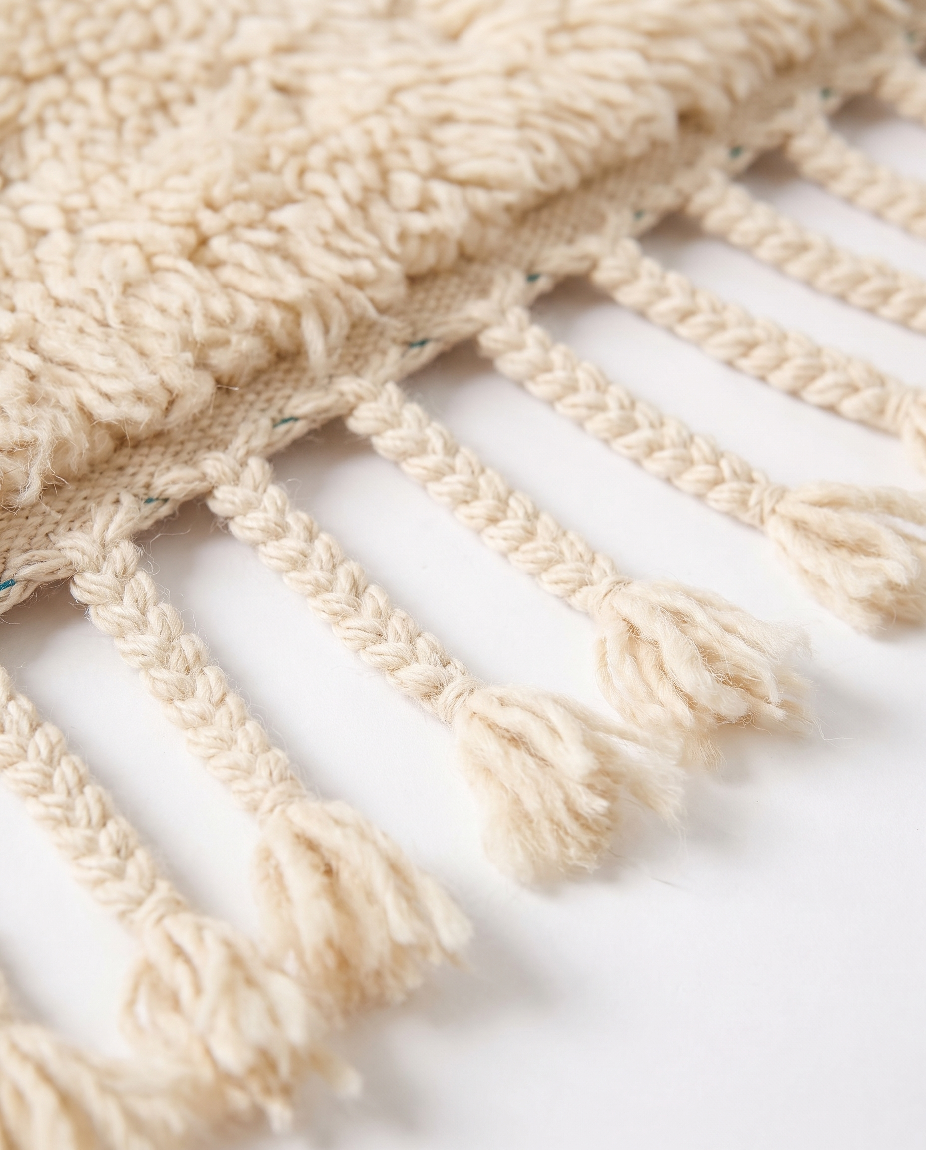 Hand-braided wool fringe tassels of premium Mrirt rug — detail on white studio background