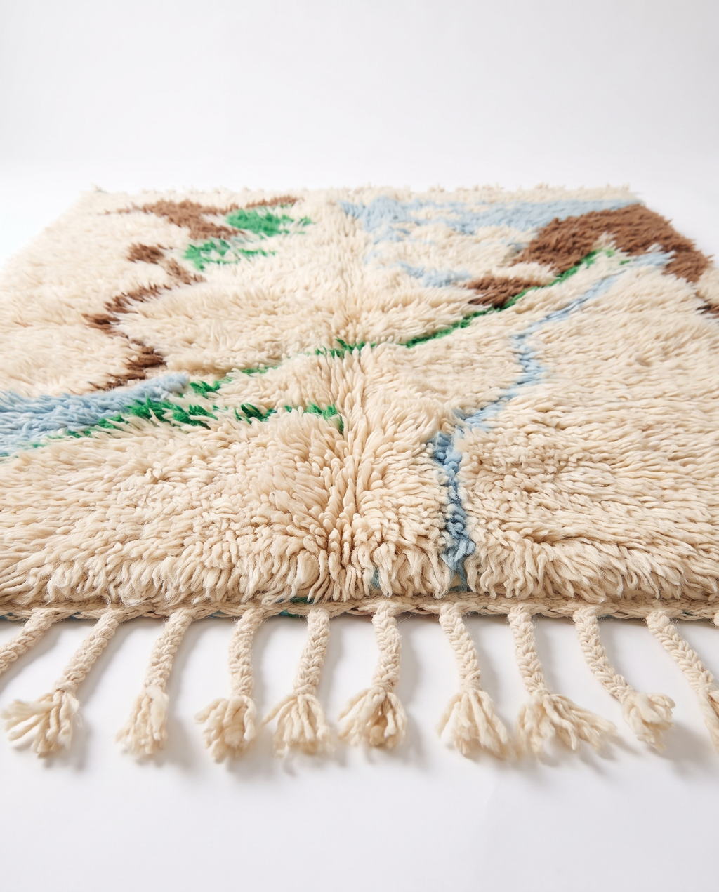 Side view of Mrirt rug showing wool pile height and braided fringe on white studio background
