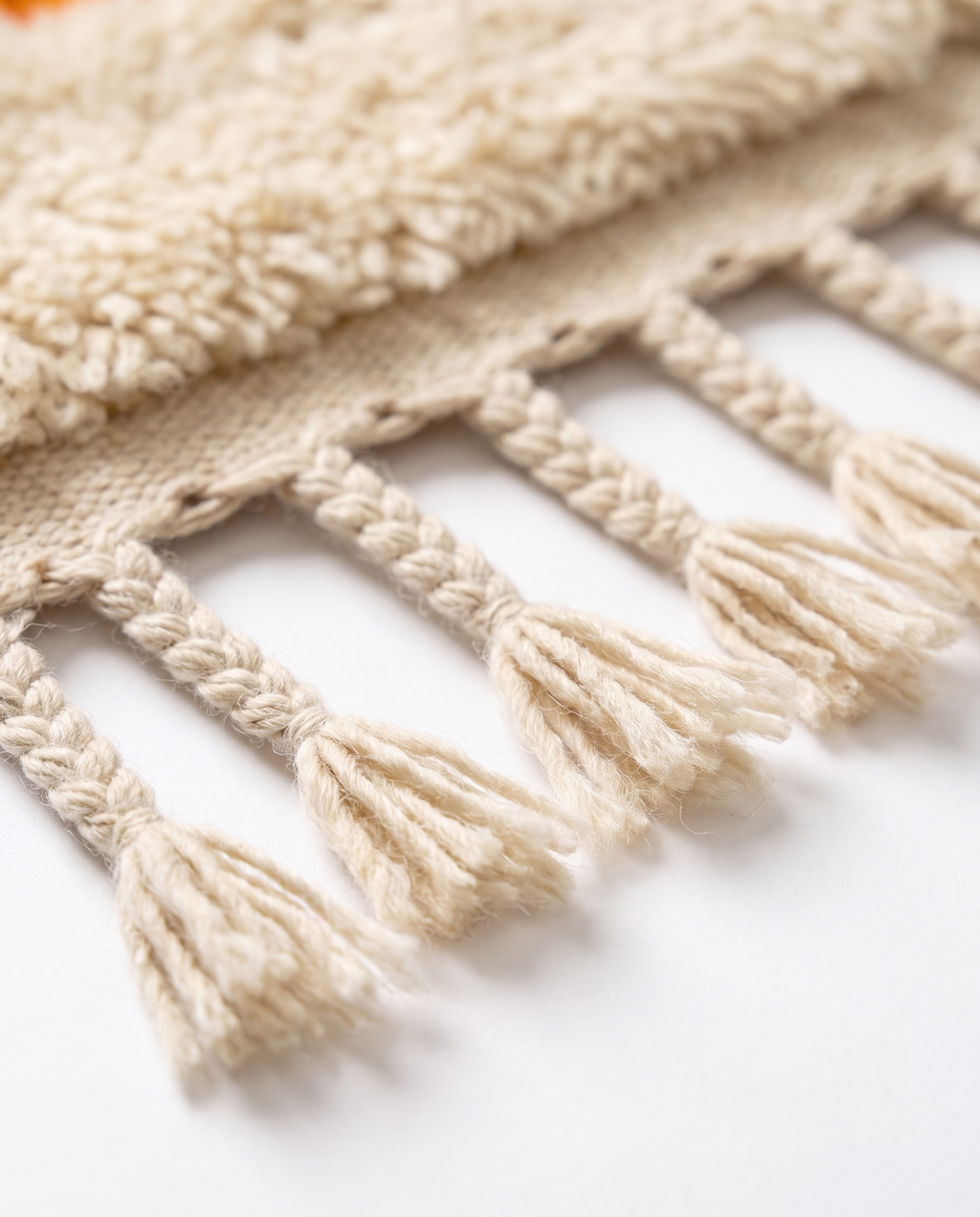 Hand-braided cream wool fringe tassels of colorful Berber runner rug on white studio background