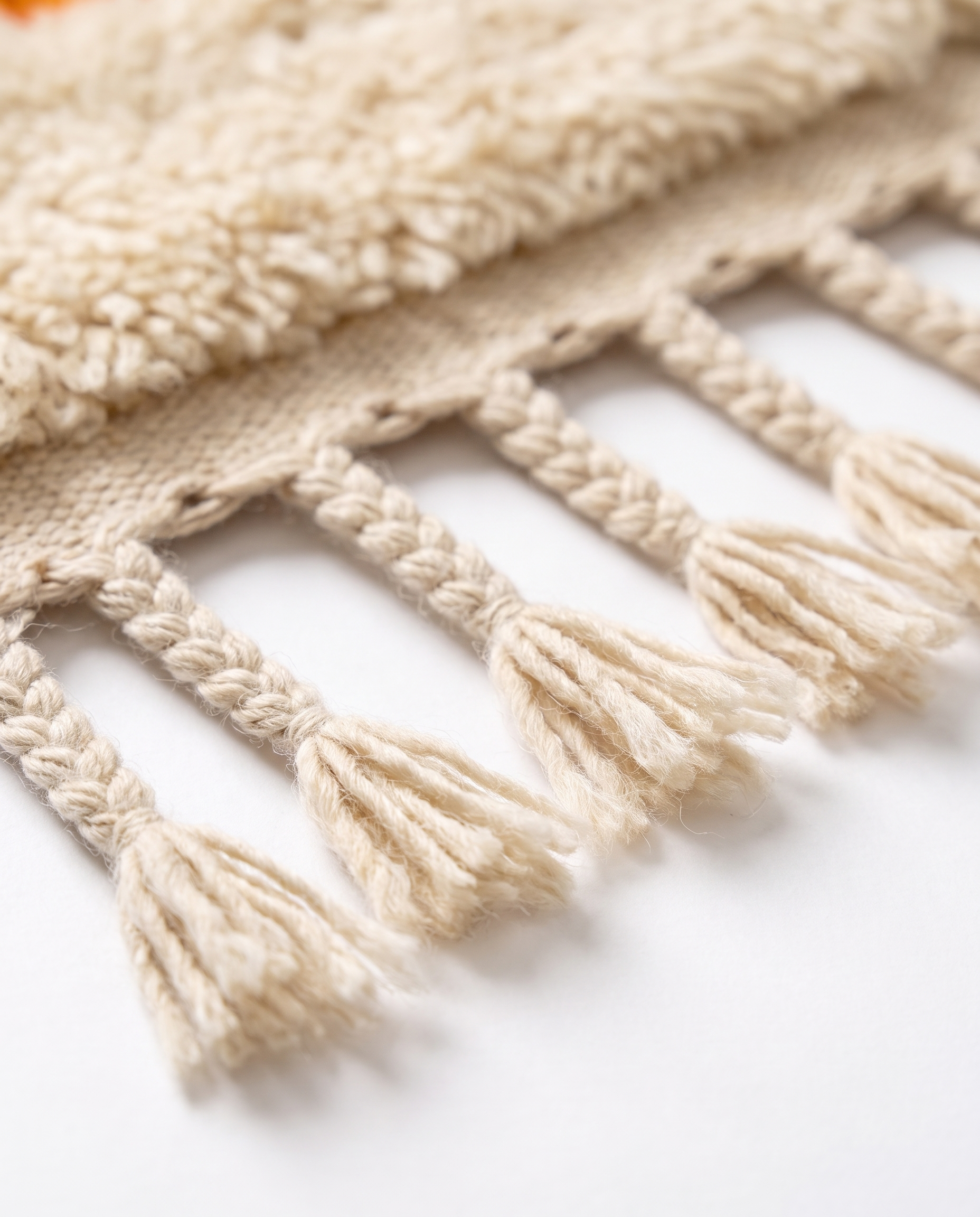Hand-braided cream wool fringe tassels of colorful Berber runner rug on white studio background