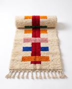 Half-rolled colorful Berber runner rug showing wool pile on white studio background