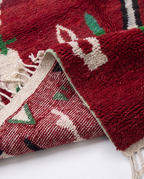 Crimson Boujaad rug folded corner showing pile and back on white studio background