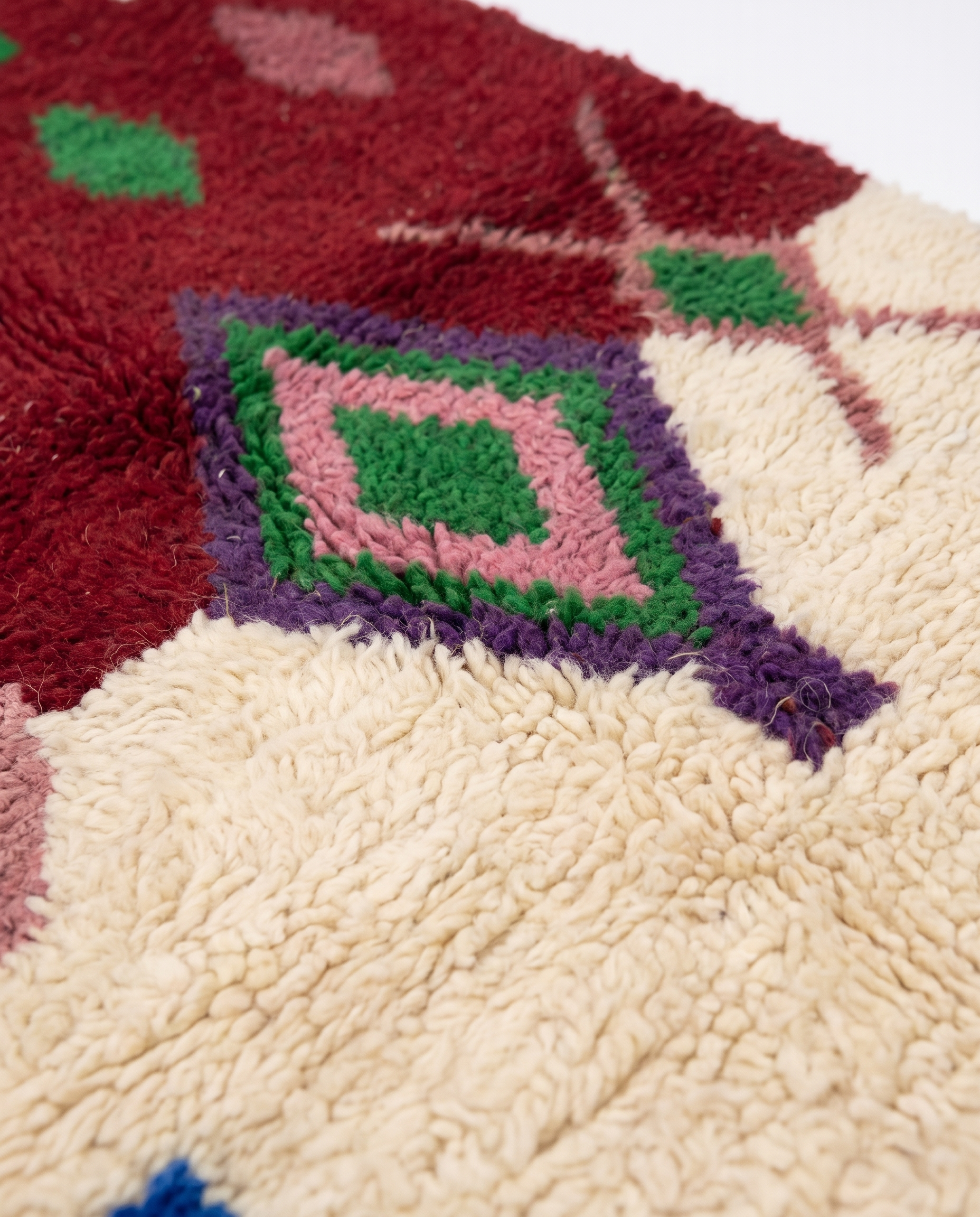 Burgundy and ivory Boujaad rug wool pile texture close-up on white studio background