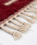 Burgundy and ivory Boujaad rug fringe detail on white studio background