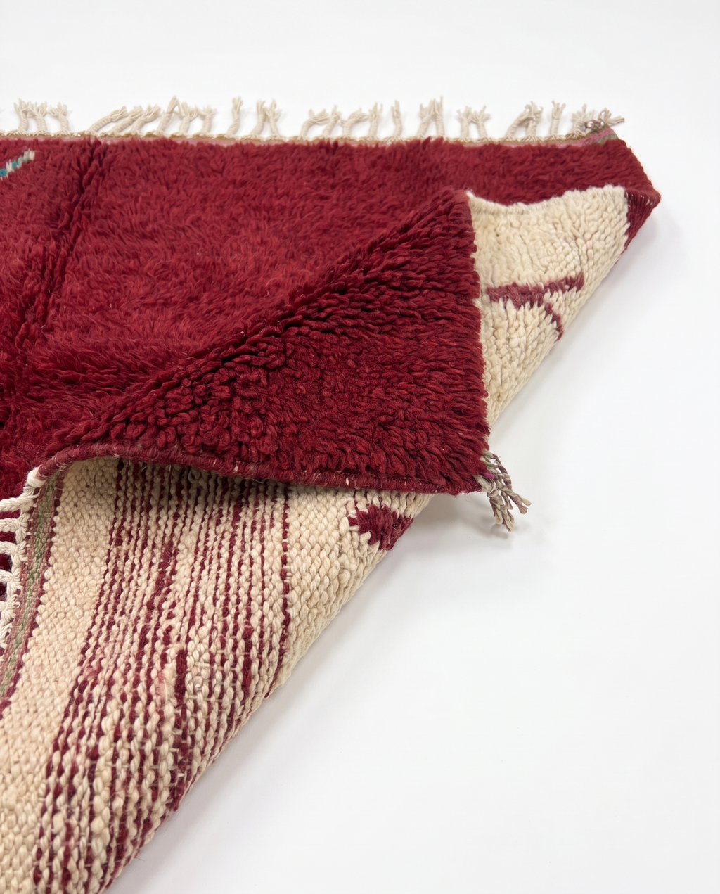 Burgundy and ivory Boujaad rug folded corner on white studio background