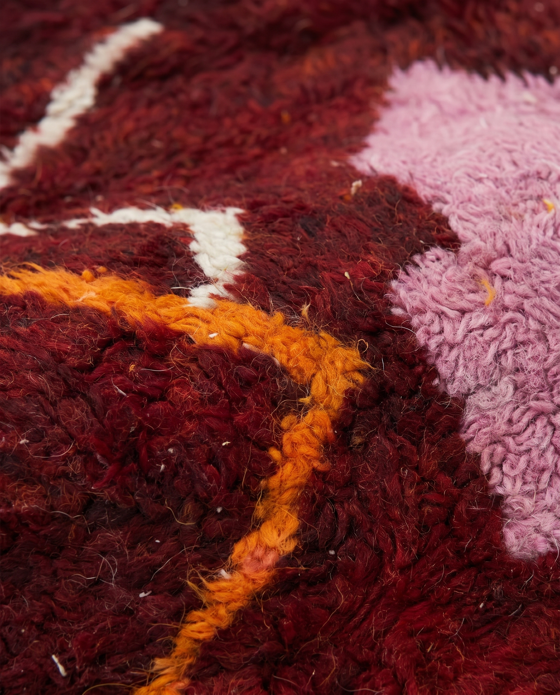 Wine red Boujaad rug wool pile texture close-up on white studio background