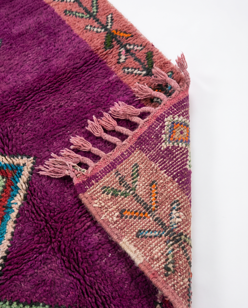 Purple Boujaad rug folded corner on white studio background