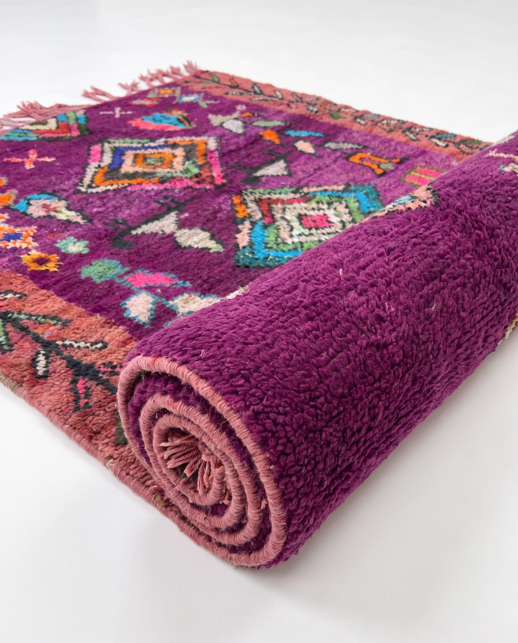 Purple Boujaad rug half-rolled on white studio background
