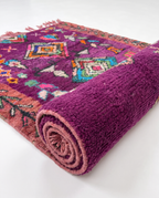 Purple Boujaad rug half-rolled on white studio background