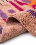 Blush terracotta Boujaad rug folded corner on white studio background