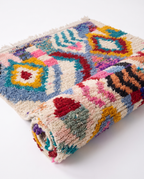Kaleidoscope Boujaad rug half-rolled on white studio background