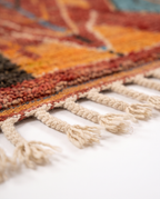 Rust and amber Boujaad rug fringe detail on white studio background