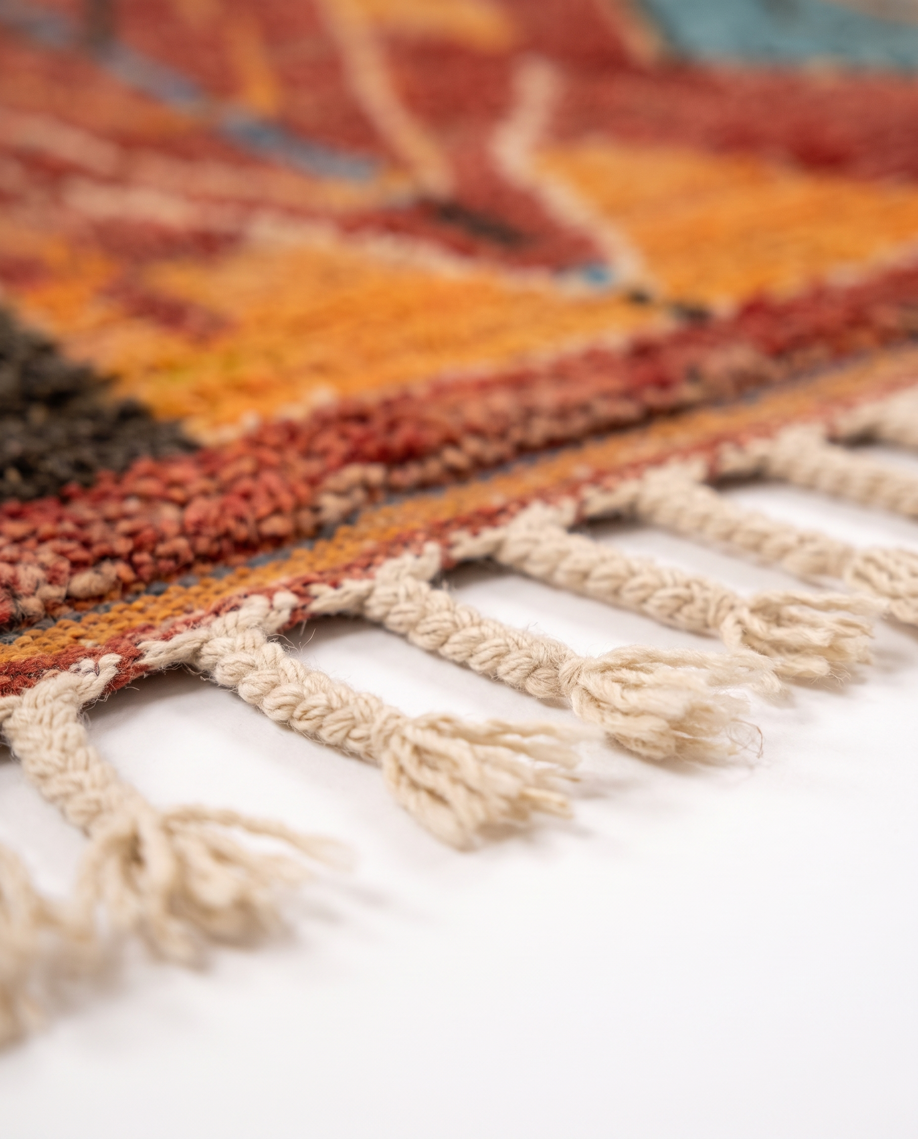 Rust and amber Boujaad rug fringe detail on white studio background