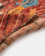 Rust and amber Boujaad rug folded corner on white studio background