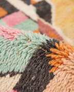 Apricot patchwork Boujaad rug wool pile texture close-up on white studio background