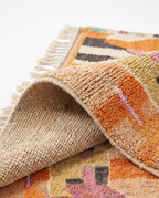 Apricot patchwork Boujaad rug folded corner on white studio background