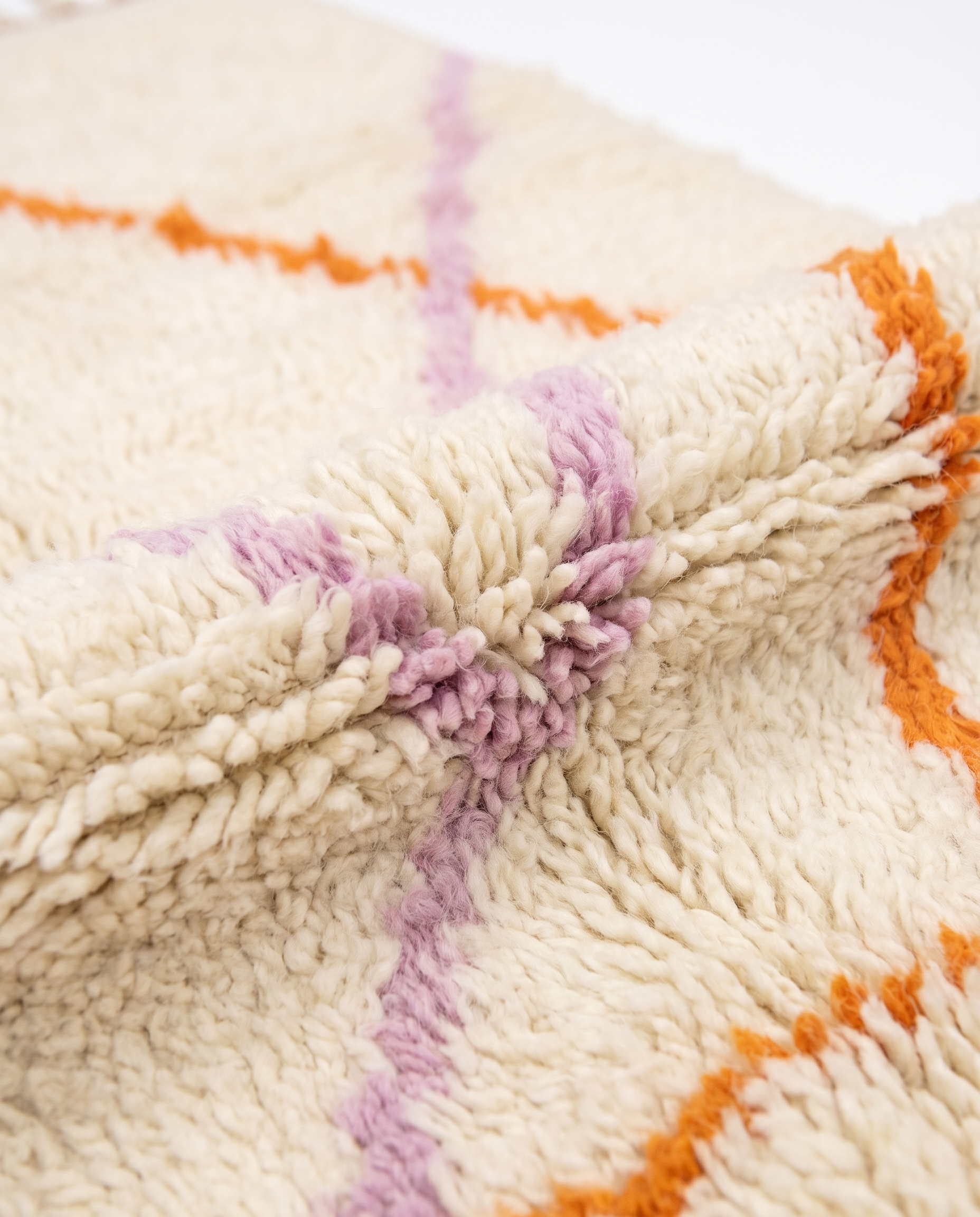 Lilac and tangerine Azilal rug wool texture close-up on white studio background