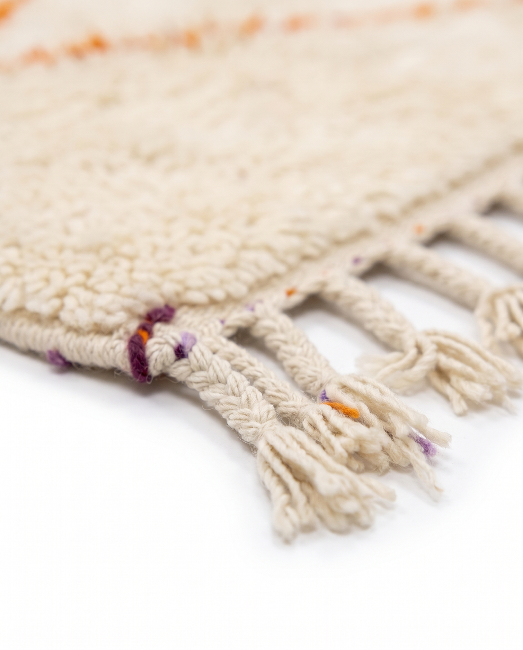 Lilac and tangerine Azilal rug fringe detail on white studio background