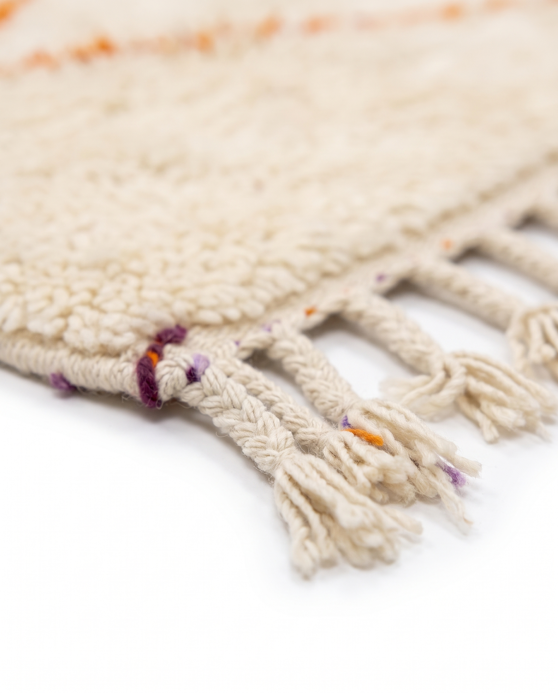 Lilac and tangerine Azilal rug fringe detail on white studio background