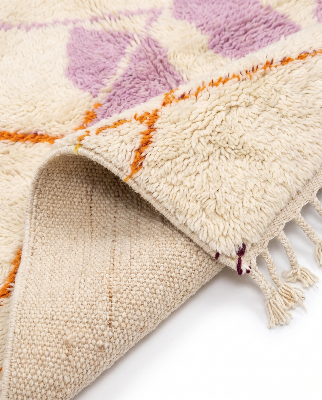 Lilac and tangerine Azilal rug folded corner on white studio background