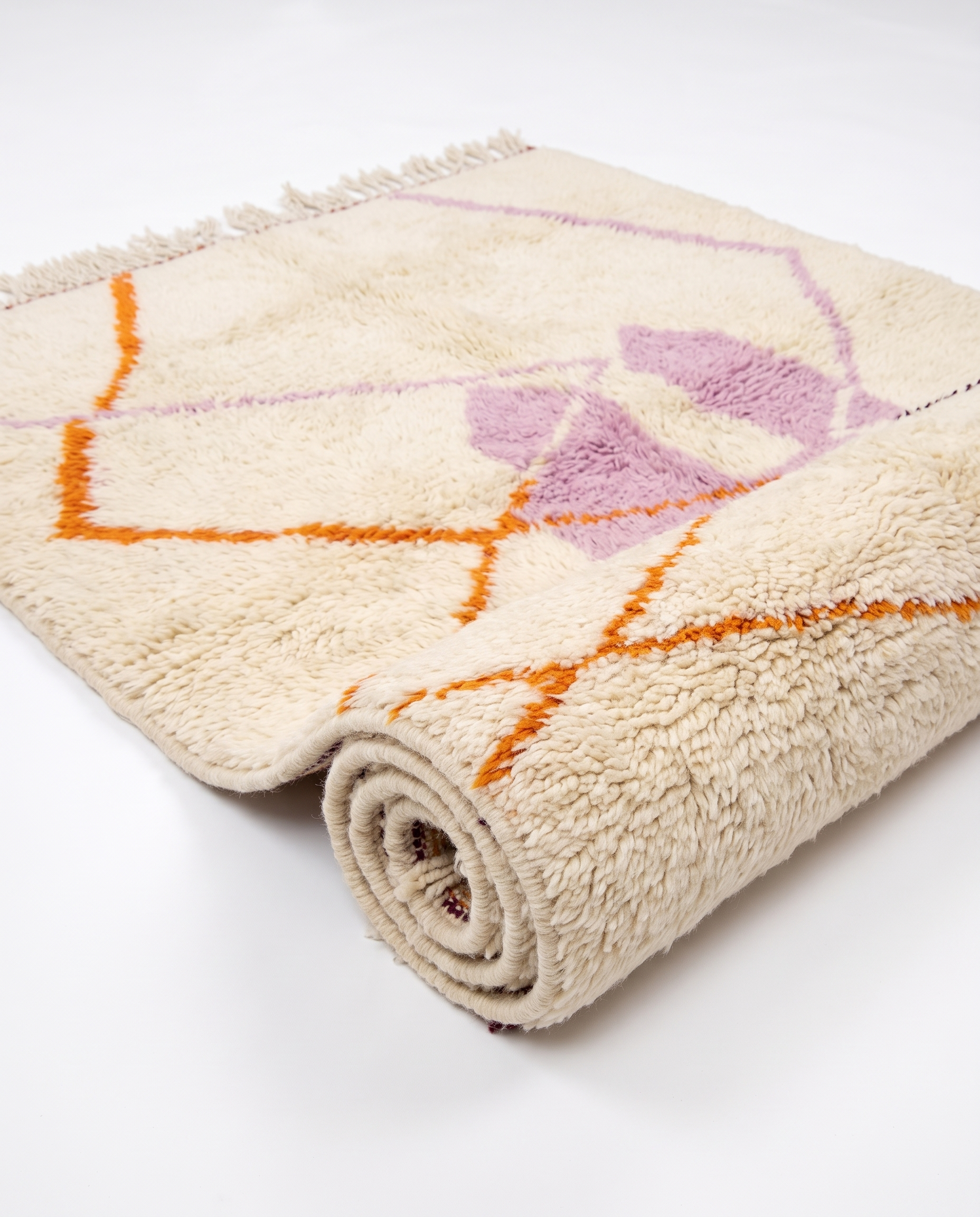 Lilac and tangerine Azilal rug half-rolled on white studio background