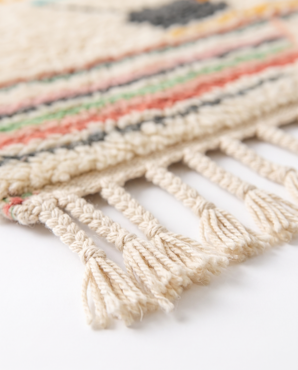 Pastel rainbow Azilal rug fringe detail on white studio background