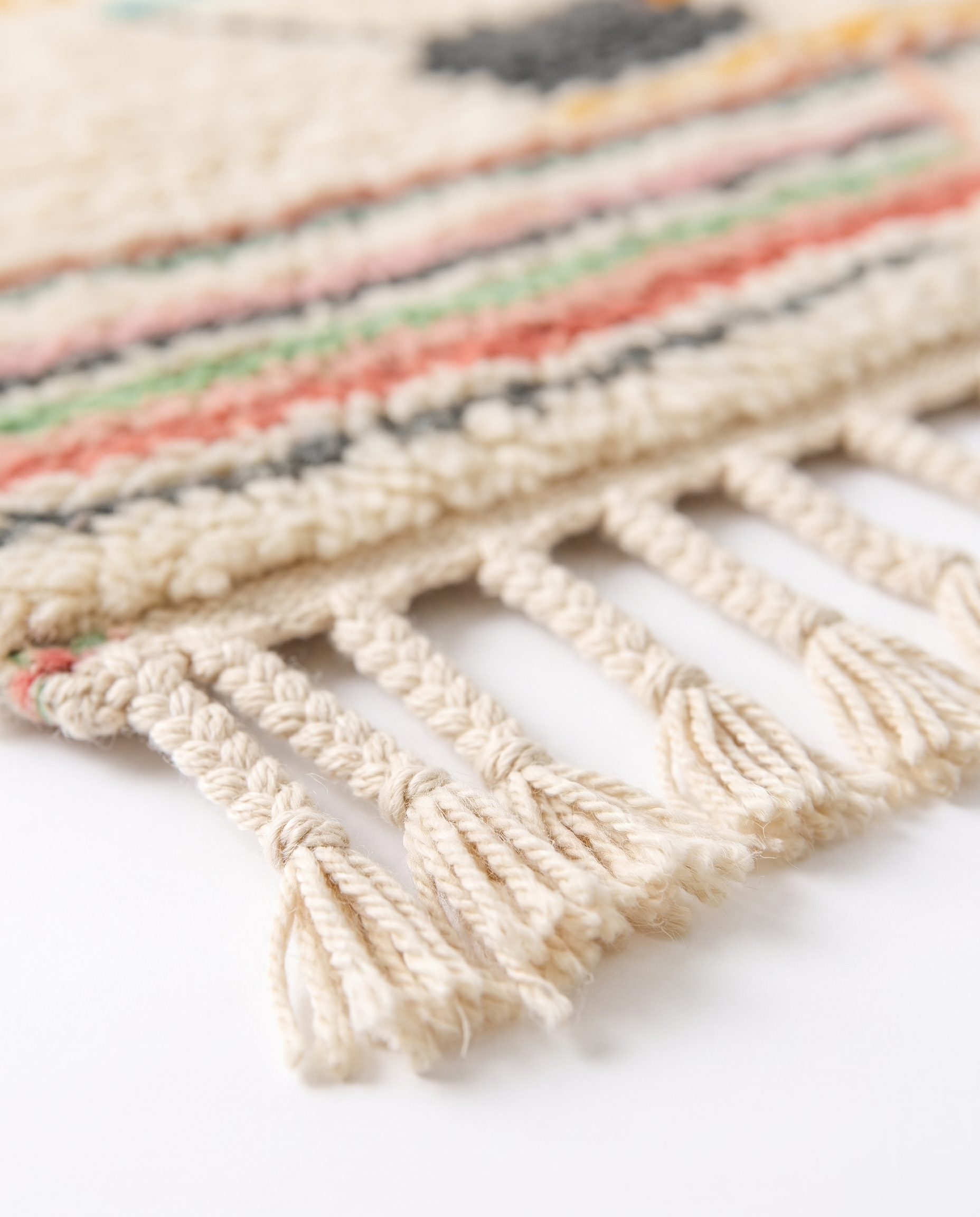 Pastel rainbow Azilal rug fringe detail on white studio background