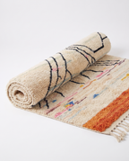 Atlas roots Azilal rug half-rolled on white studio background