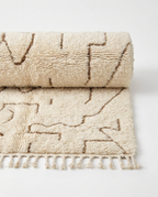 Desert lines Azilal rug half-rolled on white studio background