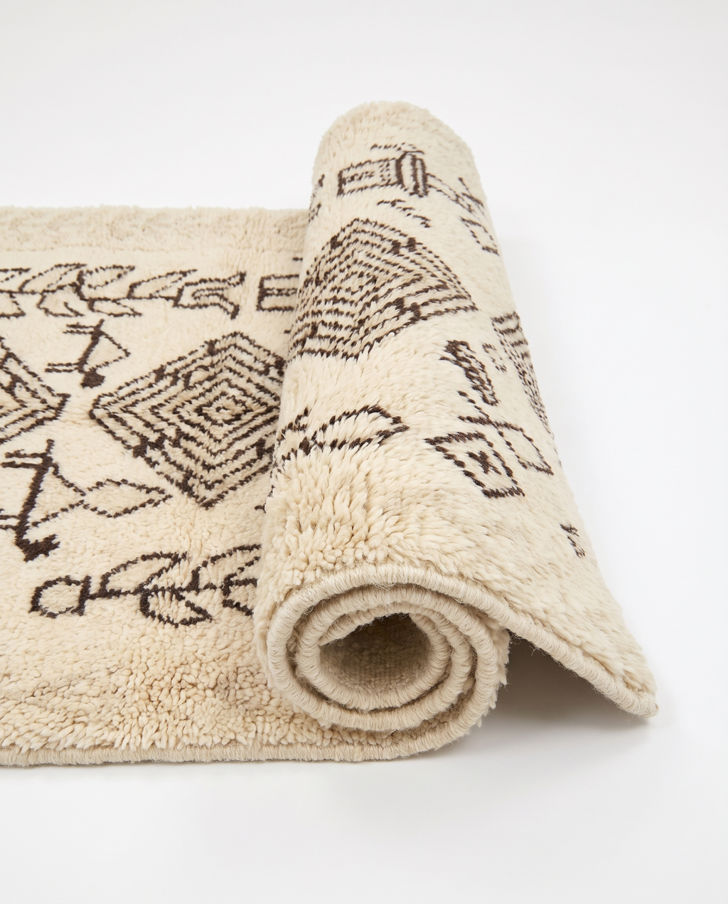 Tribal tales Azilal rug half-rolled on white studio background