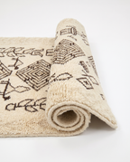 Tribal tales Azilal rug half-rolled on white studio background