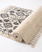 Berber script Azilal rug half-rolled on white studio background
