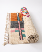 Terracotta Blocks Beni Ourain rug half-rolled on white studio background