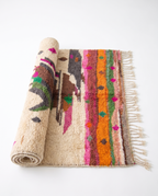 Atlas Bird Beni Ourain rug half-rolled on white studio background