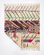 Chevron Mosaic Beni Ourain rug folded corner on white studio background