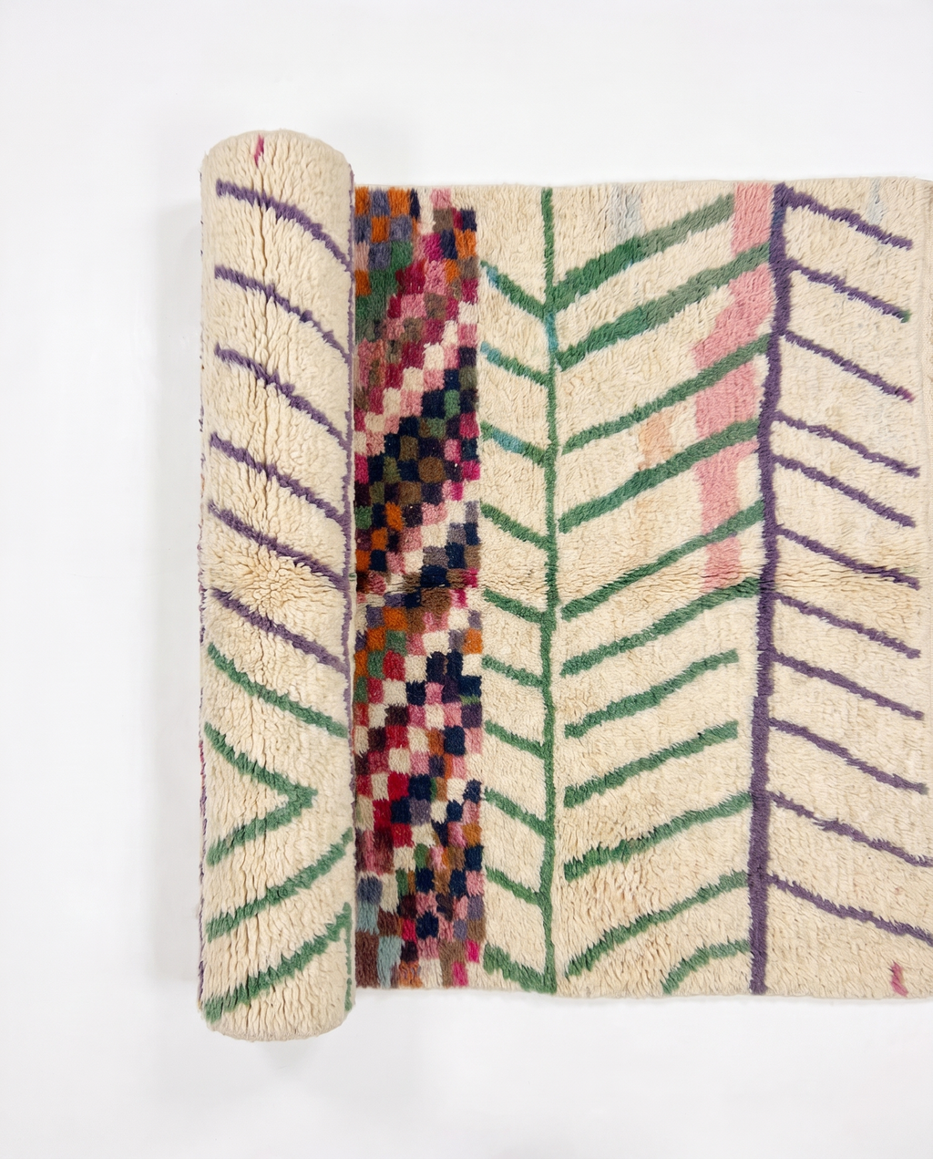 Chevron Mosaic Beni Ourain rug half-rolled on white studio background