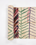 Chevron Mosaic Beni Ourain rug half-rolled on white studio background