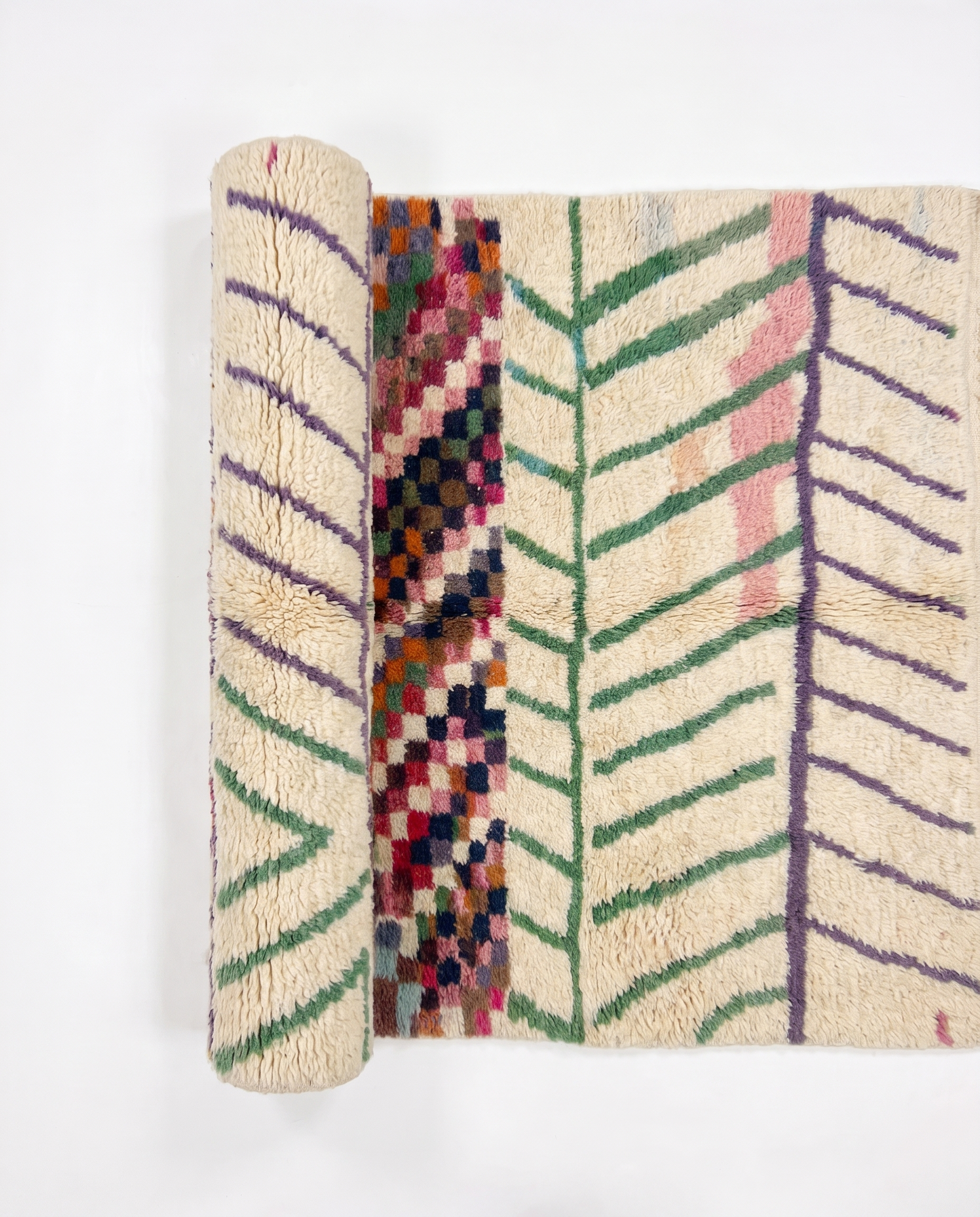 Chevron Mosaic Beni Ourain rug half-rolled on white studio background