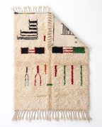 Village Signs Beni Ourain rug folded corner on white studio background