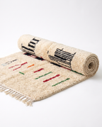 Village Signs Beni Ourain rug half-rolled on white studio background